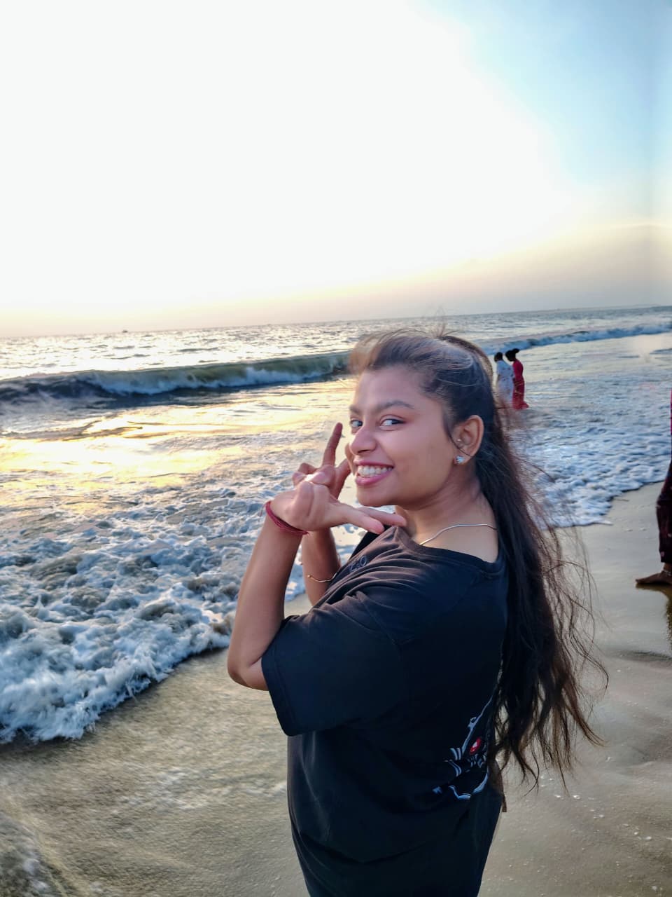 Sanskriti making a heart with her hands on a beach at sunset