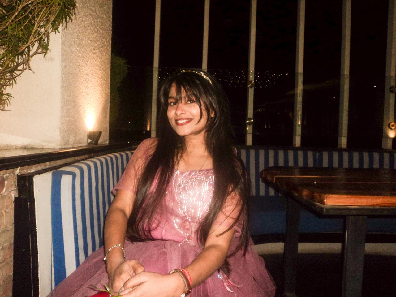 Sanskriti smiling in a pink gown at a restaurant